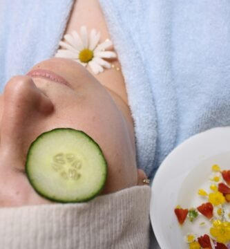 woman wearing blue robe lying with cucumber on eye